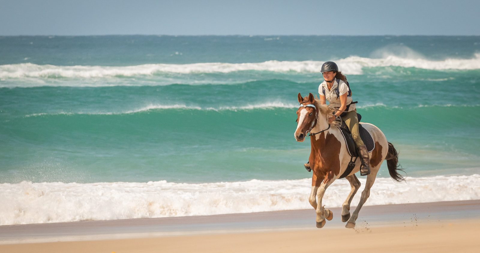 A rider galloping along the surf line on an empty beach
