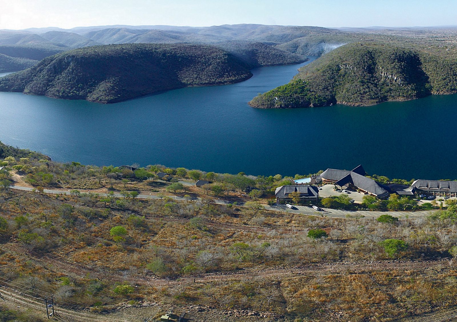 Aerial view of Lake Jozini held between wooded hills, with scattered buildings on the shoreline