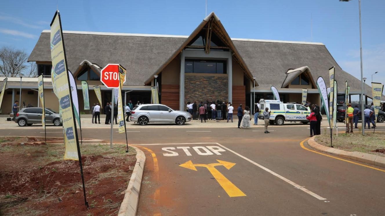 The thatched terminal building at Mkuze Airport with branded flags and vehicles outside the entrance