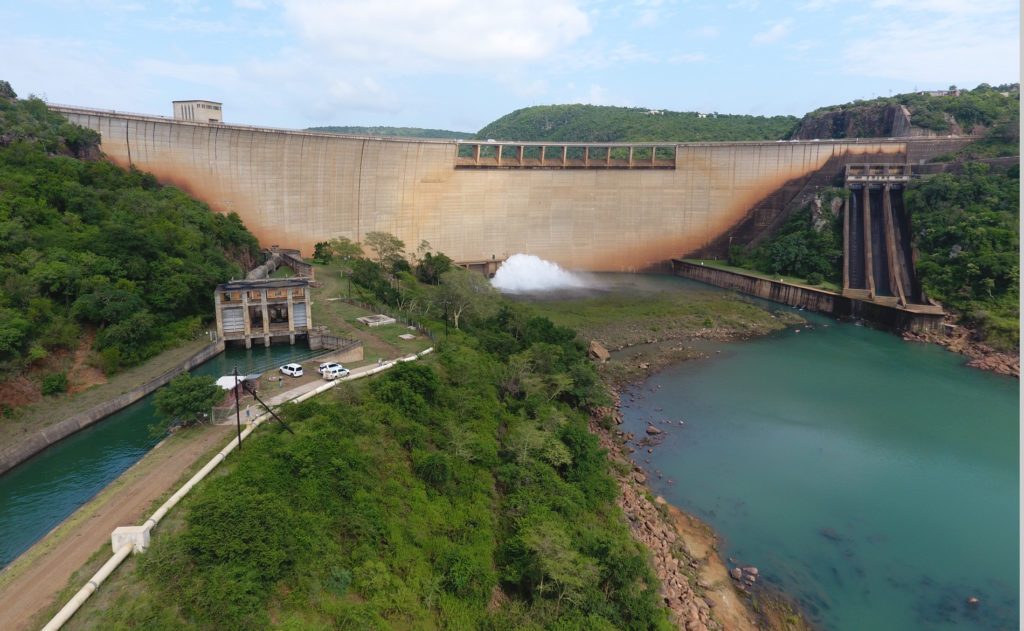 The concrete wall of Pongolapoort Dam with its outlet works and a spillway channel below