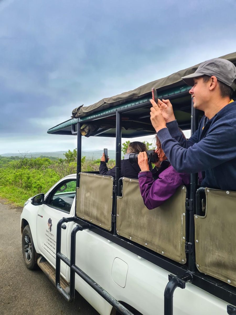 Guests photographing wildlife from an open game-drive vehicle